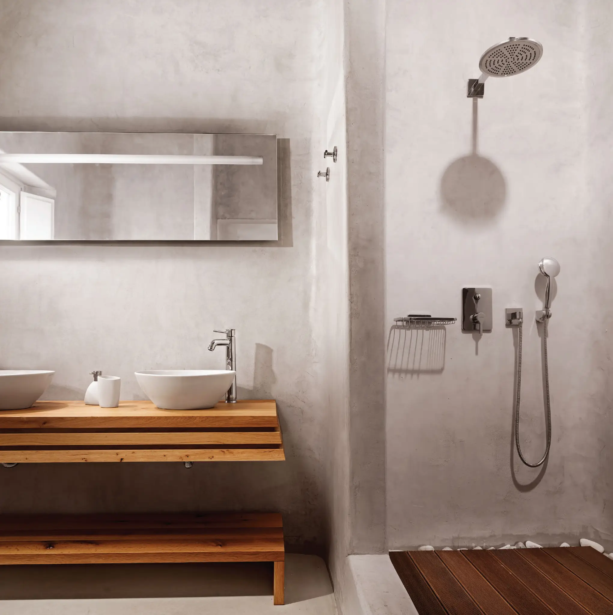 Develine Microcement gray walls and floor in a residential bathroom with an oak double vanity, two white vessel sinks, and an overhead rain shower